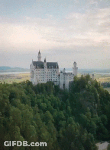 A Large White Castle Sits On Top Of A Hill GIF