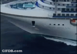 A Large White Cruise Ship Is Floating On The Ocean GIF