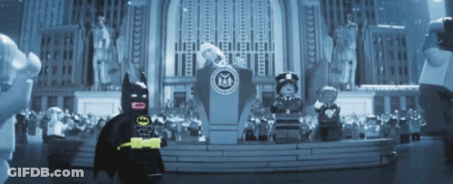 A Lego Batman Stands In Front Of A Podium In Front Of A Statue Of Liberty GIF