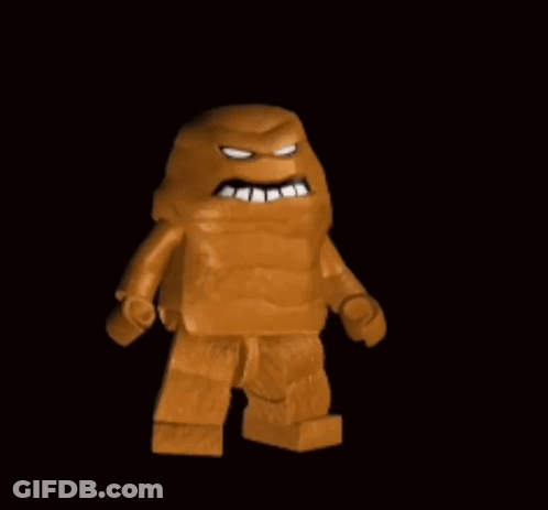 A Lego Man With A Huge Mouth Is Standing In The Dark . GIF