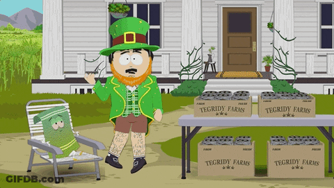 A Leprechaun Stands In Front Of A Table With Boxes Of Tegridy Farms On It GIF