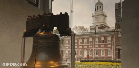 A Liberty Bell Stands In Front Of A Building GIF