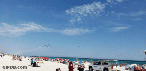 A Lifeguard Truck Is Parked On The Beach Near A Crowd Of People GIF