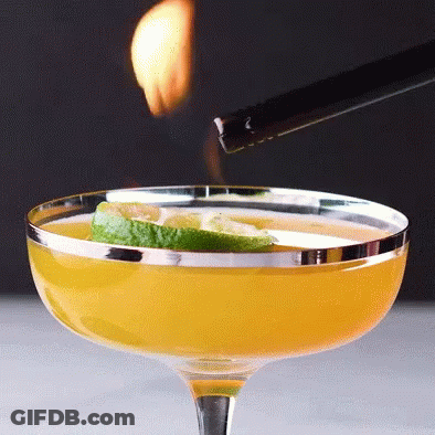 A Lighter Is Being Used To Light A Drink In A Coupe Glass GIF