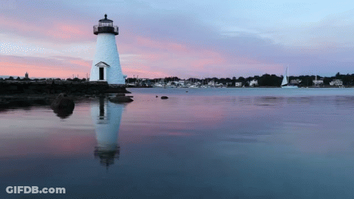 A Lighthouse In The Middle Of A Body Of Water At Sunset GIF
