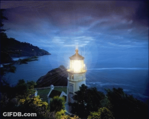 A Lighthouse On A Hill Overlooking A Body Of Water At Night GIF