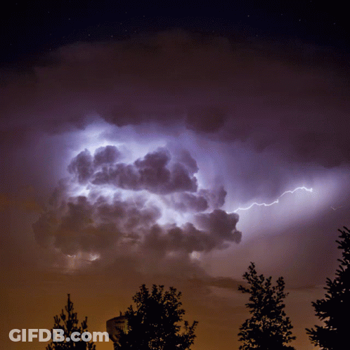 A Lightning Bolt Strikes A Cloud In A Dark Sky GIF