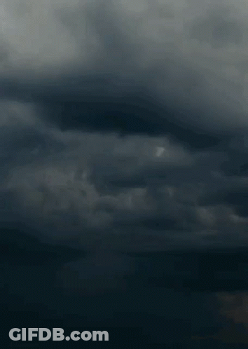A Lightning Bolt Strikes In A Dark Cloudy Sky . GIF