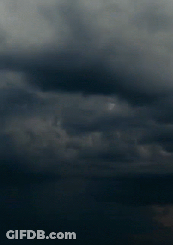 A Lightning Bolt Strikes In The Dark Cloudy Sky GIF
