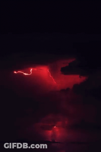 A Lightning Bolt Strikes Through A Cloudy Sky At Night GIF