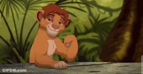 A Lion Cub From The Lion King Is Sitting On A Wooden Table . GIF