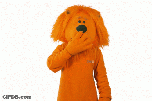 A Lion Mascot Covering His Mouth With His Hand While Wearing An Orange Sweater That Says Nb GIF