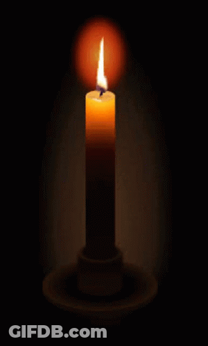 A Lit Candle In A Dark Room With A Candle Holder GIF