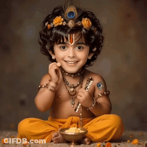 A Little Boy Dressed As Krishna Is Sitting On The Ground With A Bowl Of Food GIF