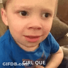 A Little Boy In A Blue Shirt Is Making A Funny Face While Sitting On A Couch . GIF