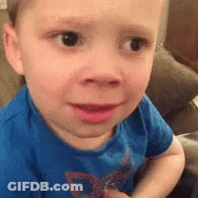 A Little Boy In A Blue Shirt Is Sitting On A Couch . GIF