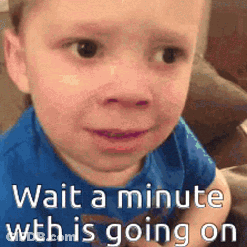 A Little Boy In A Blue Shirt Is Sitting On A Couch With The Words `` Wait A Minute Wth Is Going On '' . GIF