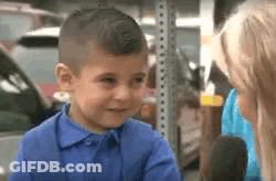 A Little Boy In A Blue Shirt Is Talking To A Woman In A Parking Lot . GIF