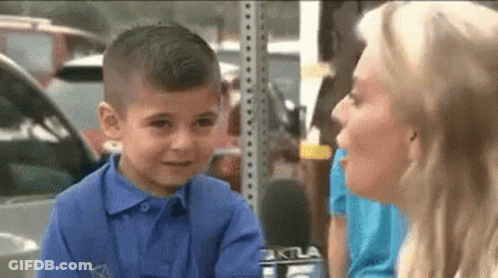 A Little Boy In A Blue Shirt Is Talking To A Woman With A Microphone . GIF