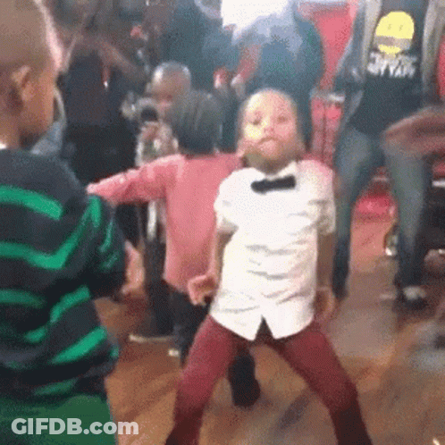 A Little Boy In A Bow Tie Is Dancing In A Crowd . GIF