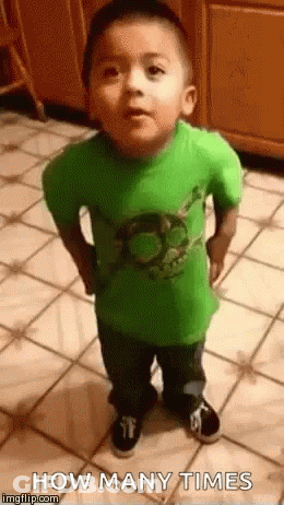 A Little Boy In A Green Shirt Is Standing On A Tiled Floor And Looking At The Camera . GIF