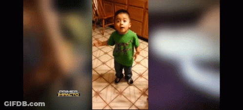 A Little Boy In A Green Shirt Is Standing On A Tiled Floor . GIF