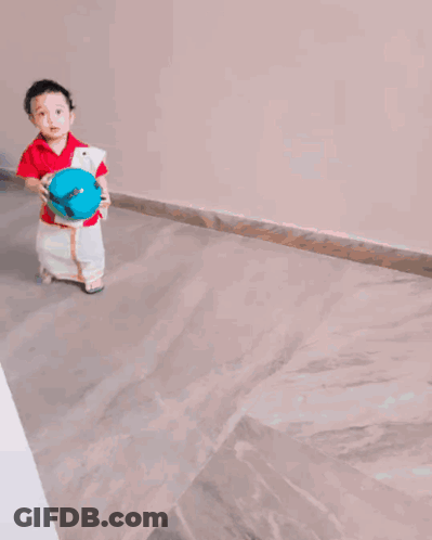 A Little Boy In A Red Shirt And White Pants Holds A Blue Ball GIF