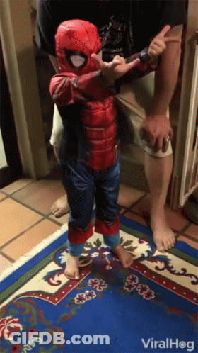 A Little Boy In A Spiderman Costume Is Standing On A Blue Rug GIF