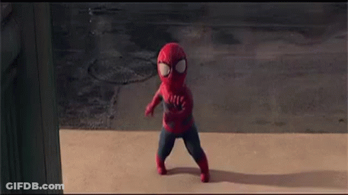 A Little Boy In A Spiderman Costume Is Walking Down The Sidewalk . GIF