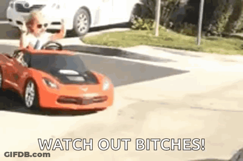 A Little Boy Is Driving A Toy Car Down The Street . GIF