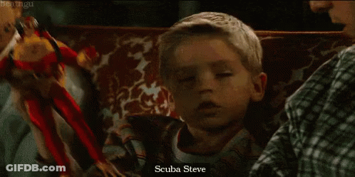 A Little Boy Is Holding A Toy That Says Scuba Steve On It GIF