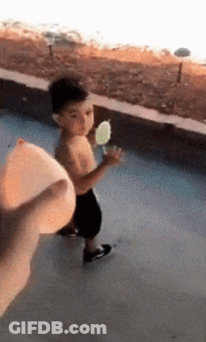 A Little Boy Is Holding An Ice Cream Cone In His Hand While Walking Down The Street . GIF