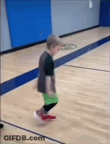 A Little Boy Is Jumping On A Wooden Basketball Court . GIF