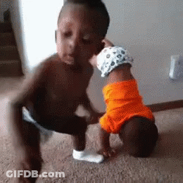 A Little Boy Is Kissing A Baby On The Cheek . GIF