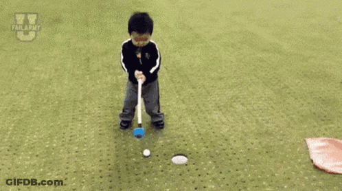 A Little Boy Is Laying On The Ground Near A Hole In The Grass . GIF