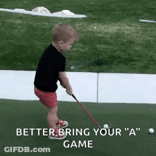 A Little Boy Is Playing Golf On A Green And Holding A Golf Club . GIF