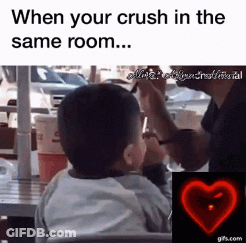 A Little Boy Is Sitting At A Table With A Man Taking A Picture Of Him With A Cell Phone .. GIF