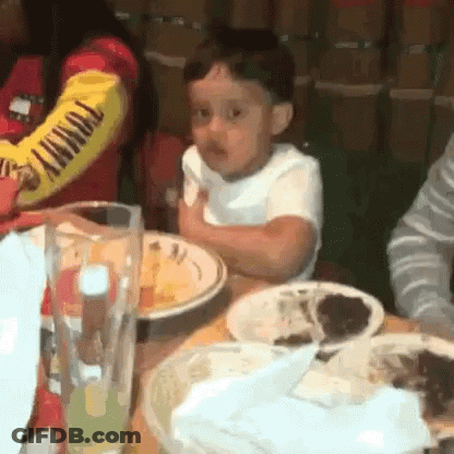 A Little Boy Is Sitting At A Table With Plates Of Food And A Glass Of Beer . GIF
