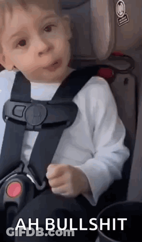 A Little Boy Is Sitting In A Car Seat And Making A Face . GIF