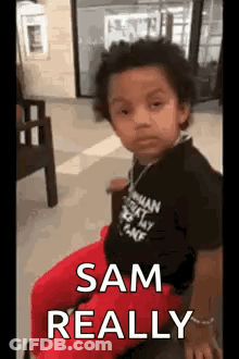 A Little Boy Is Sitting In A Chair With The Words `` Sam Really '' Written On The Screen . GIF