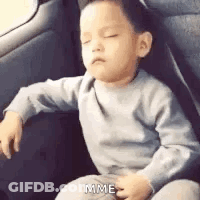 A Little Boy Is Sitting In The Back Seat Of A Car . GIF