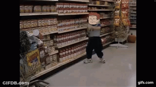 A Little Boy Is Standing In A Grocery Store Holding A Bottle Of Tomato Sauce . GIF