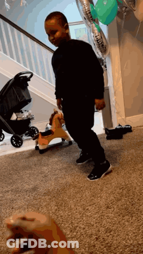 A Little Boy Is Standing In Front Of A Rocking Horse And Balloons That Say ' Daddy ' On Them GIF
