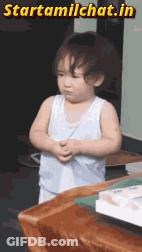 A Little Boy Is Standing In Front Of A Wooden Table With The Words Starttamilchat.in Written Above Him GIF