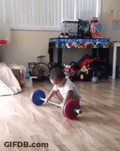 A Little Boy Playing With A Barbell On The Floor GIF