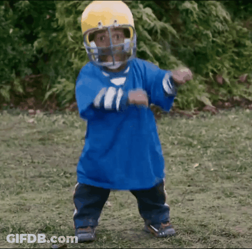 A Little Boy Wearing A Blue Shirt And A Yellow Helmet Is Dancing GIF