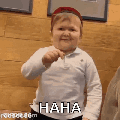 A Little Boy Wearing A Hat And A White Shirt Is Laughing And Holding A Key . GIF