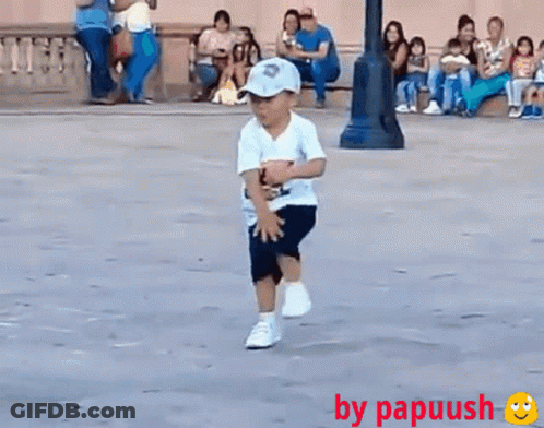 A Little Boy Wearing A Hat And A White Shirt Is Running On The Street GIF