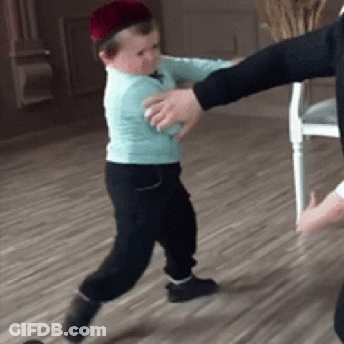A Little Boy Wearing A Hat Is Being Held By A Man GIF