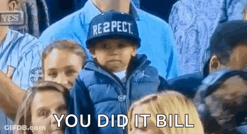 A Little Boy Wearing A Hat That Says Respect Is Sitting In A Crowd Of People . GIF